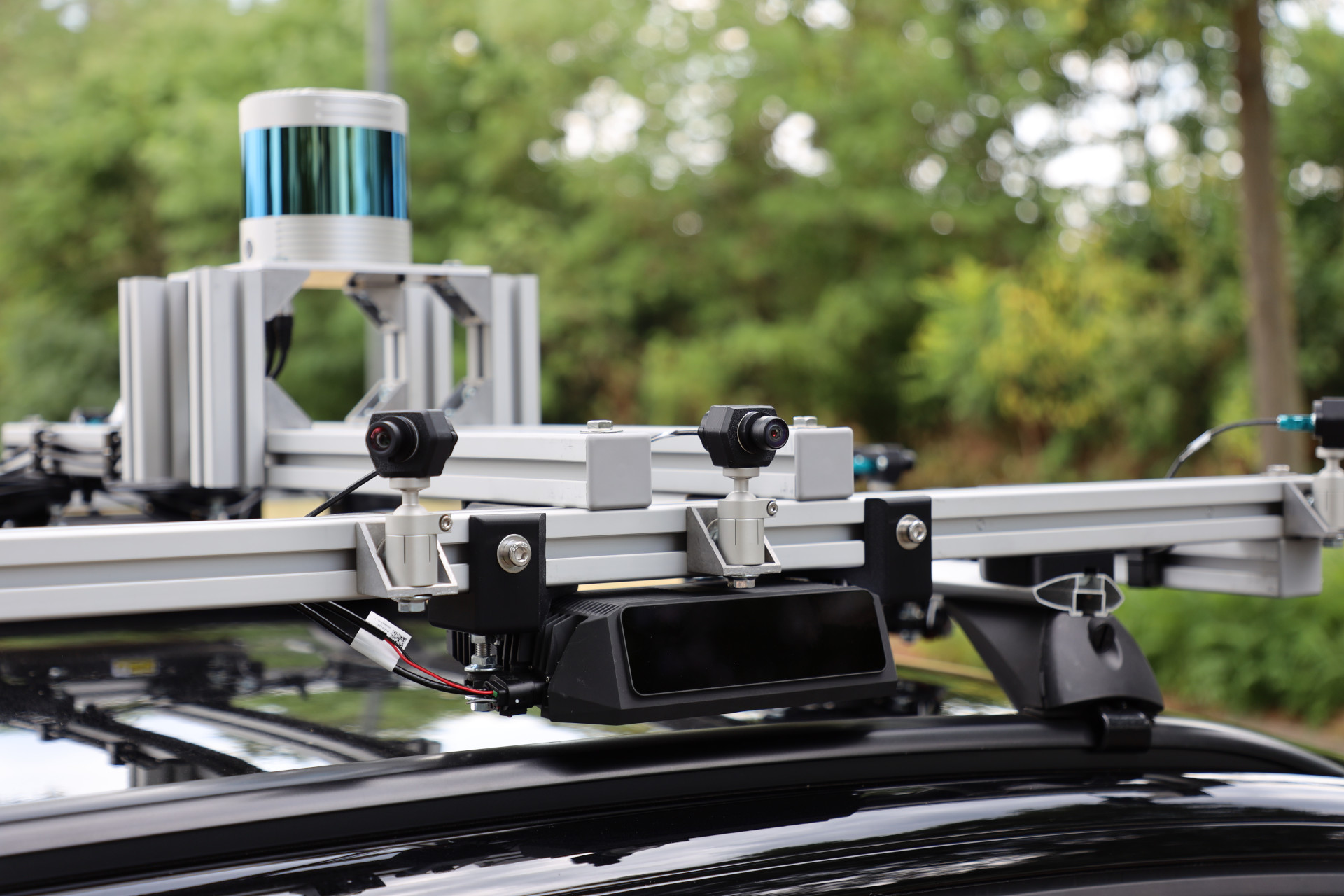 Close-up of the rear of the roof rack showing cameras on ball joints, a long-range lidar, and the 360 degree lidar on its tower.