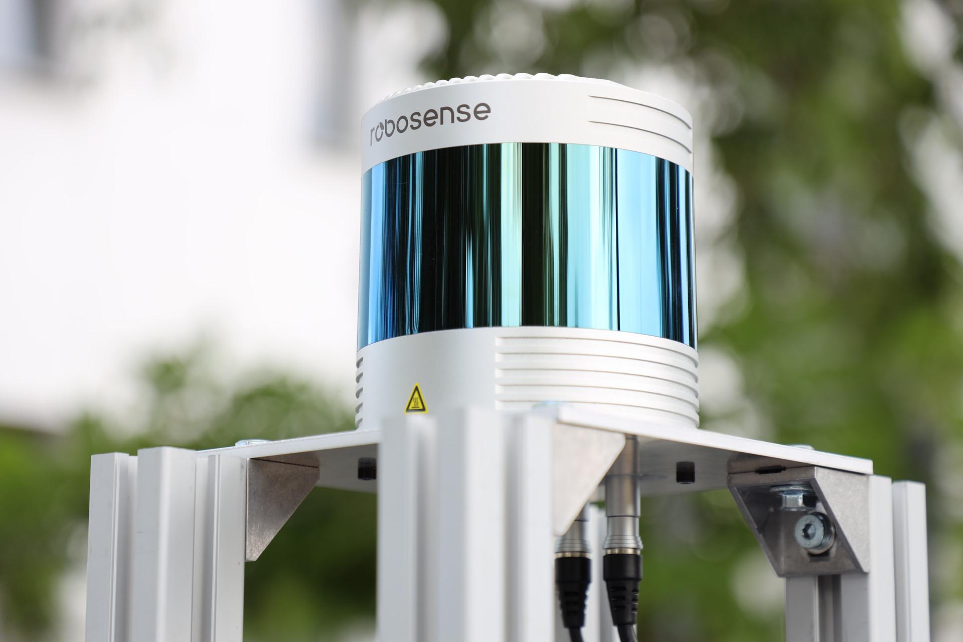 Close-up of the RoboSense Ruby Plus 360 degree lidar mounted on its leveled aluminum tower above the rest of the sensor rack.